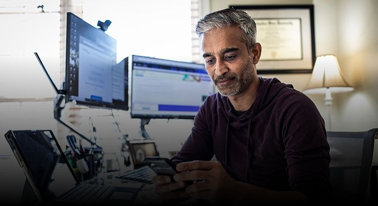 Man on mobile phone with computer monitors behind him